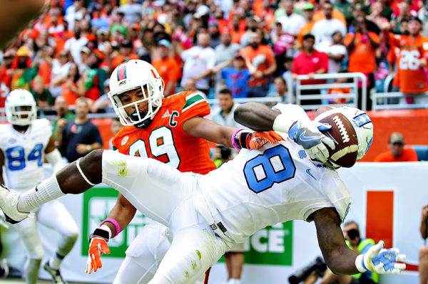 Hurricanes DB, Corn Elder tries to knock the ball away from RB, T.J. Logan of the Tar Heels