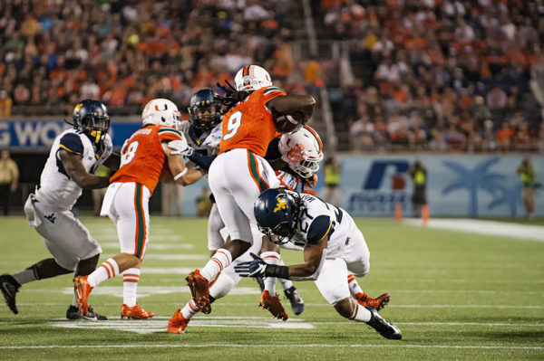 Malcom Lewis, Hurricanes WR, tries to leap past a defender from West Virginia