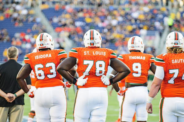 Miami Hurricane players watch their teammates battle in warmups