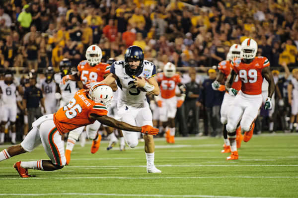 West Virginia QB, Skyler Howard, tries to rush past the Hurricanes defense