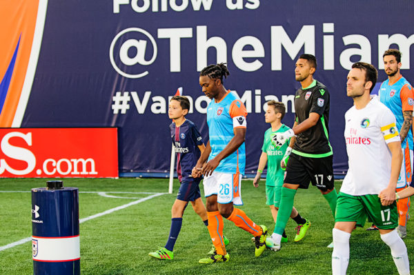 Players walk out with kids prior to the match